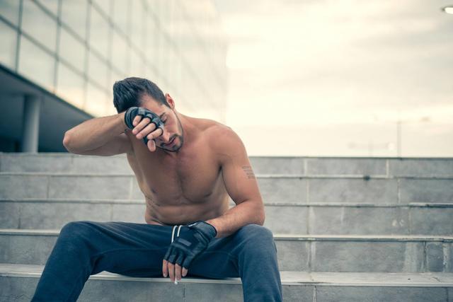 Young-man-relaxing-and-wiping-sweat-from-his-face-after-very-heavy-workout.jpg