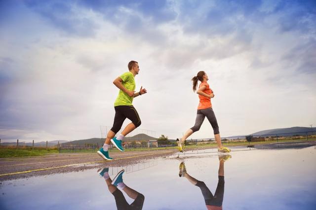 Young-couple-running-on-asphalt-in-rainy-weather-splashing-in-puddles..jpg